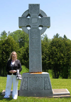 ANNE KELLY is shown above at the Celtic cross which stands beside the memorial in the Martindale Pioneer Cemetery. The cross which was designed by Ethna O’Kane of Belfast depicts the journey across the ocean on the famine ships to the hope of a better future in North America.