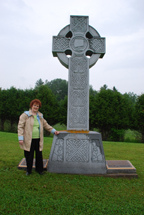 CATHOLINE BUTLER of The Celtic Connection stands beside the 12-foot Celtic cross at Martindale Pioneer Cemetery in western Quebec. She was instrumental in erecting this monument and cross in memory of the survivors of the Irish Famine.