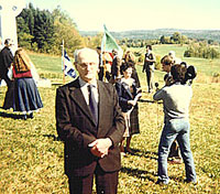 MARTIN BROWN dressed in his Sunday best stands for a photo as Catholine speaks to Skyline TV at the memorial ceremony for the Celtic cross at Martindale Pioneer Cemetery.